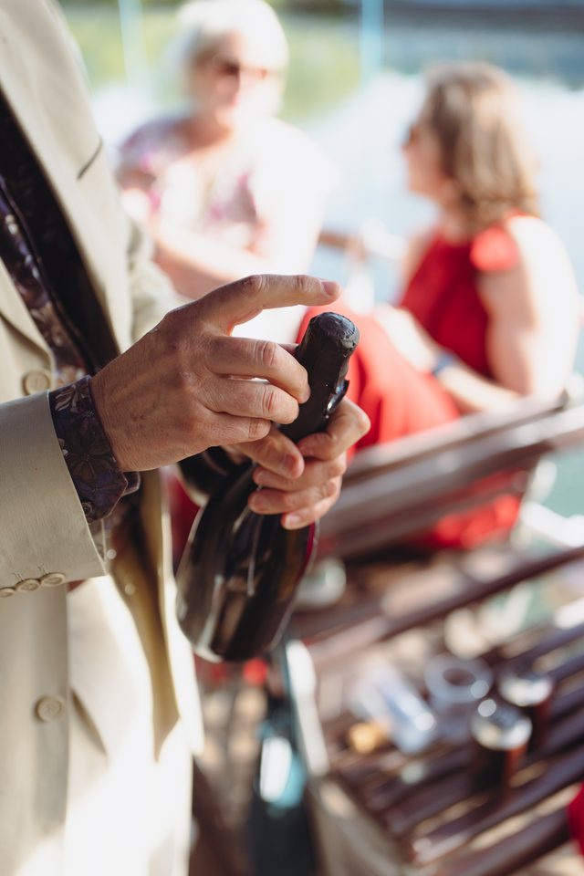 A person holds a champagne bottle, with blurred guests in the background.