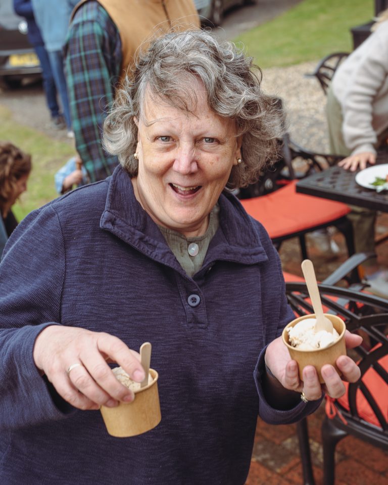 Person holding two ice cream cups outdoors.