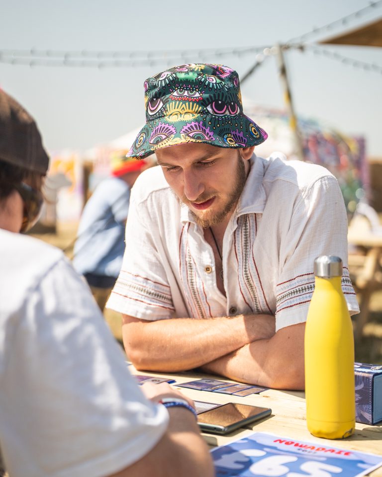 Two people playing cards at a table under bright sun.
