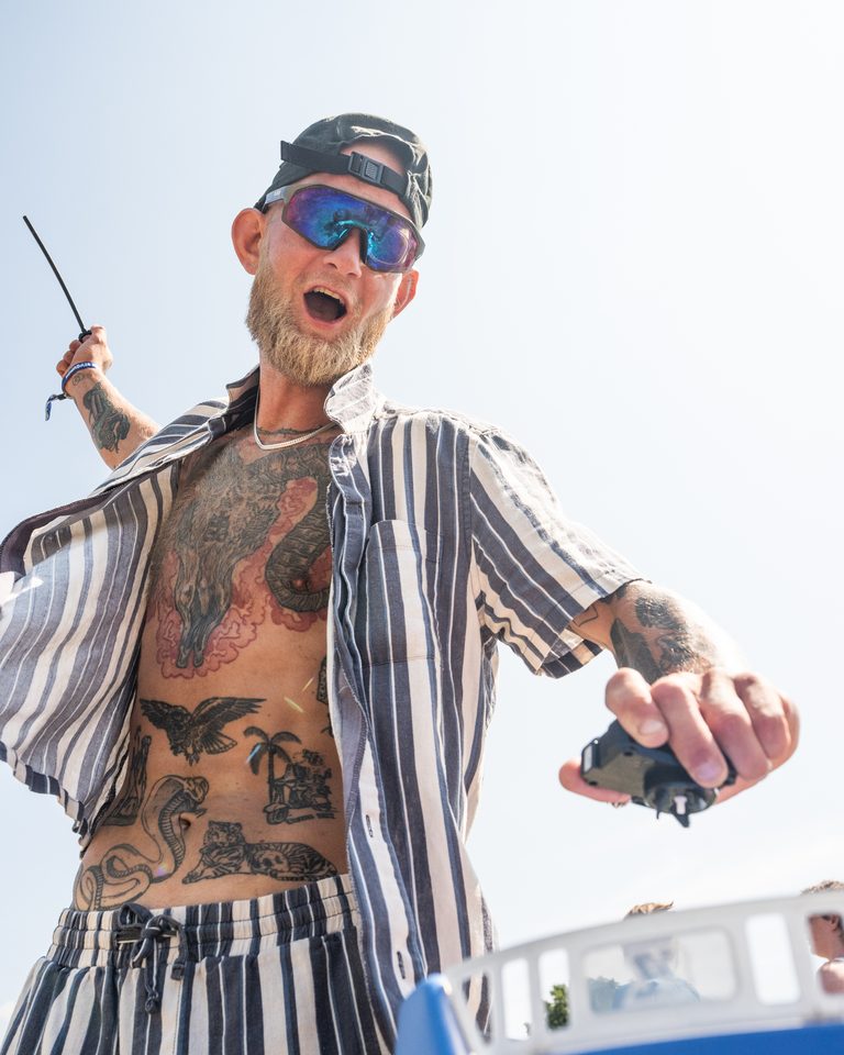 Person with tattoos and sunglasses performing outdoors under bright sun.
