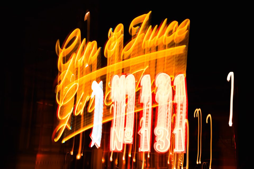 Blurred neon sign glowing at night, with motion trails against dark sky.
