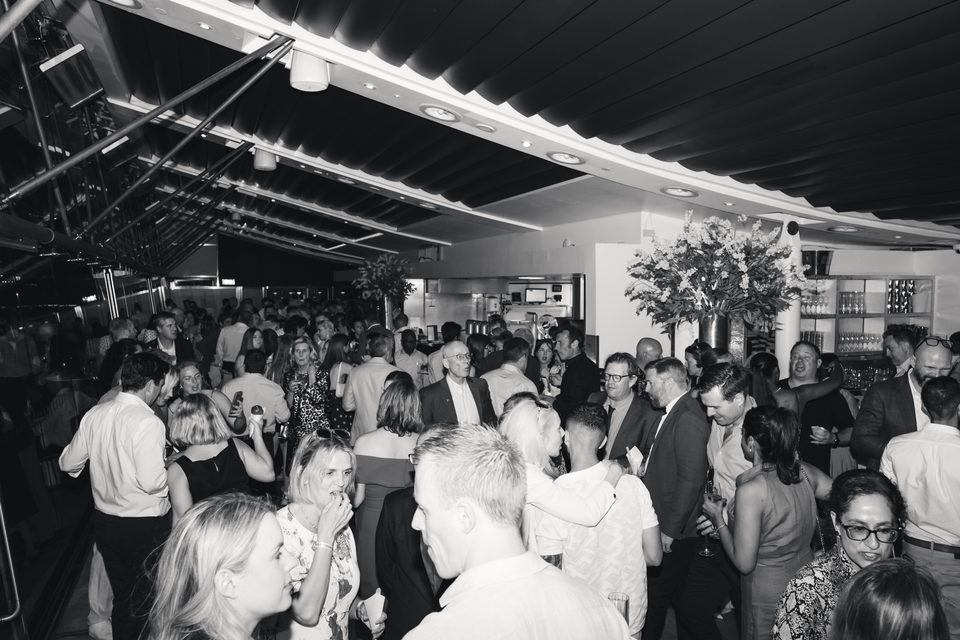 Crowded indoor venue with people mingling under artificial lighting.
