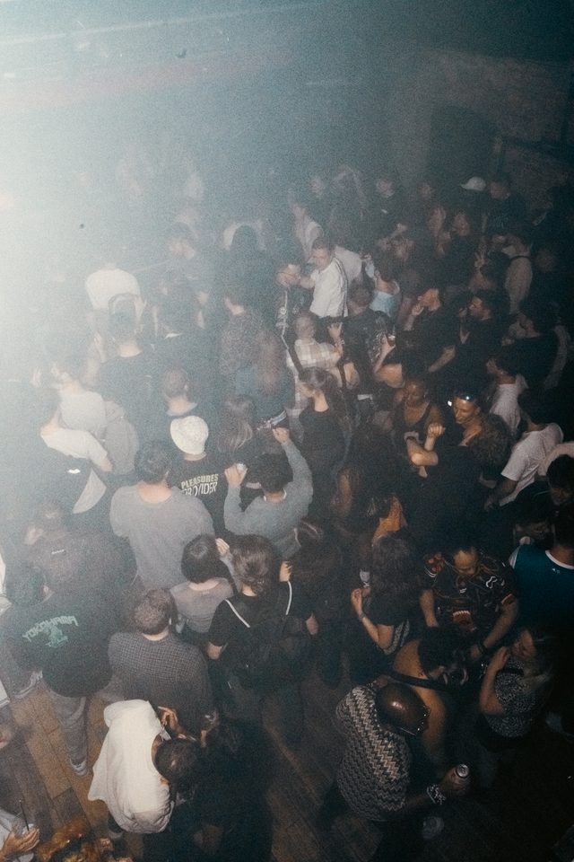 Crowd dancing in dimly lit club with haze and smoke.