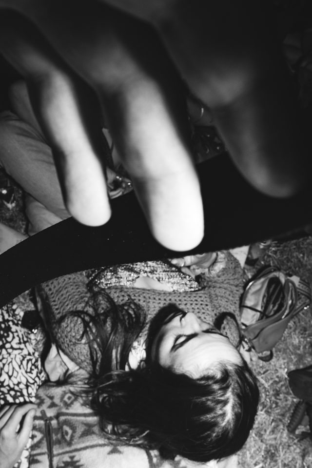 Black and white image of a hand above a sleeping person on a blanket.