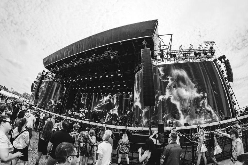 Large outdoor festival stage with crowd and dynamic lighting.
