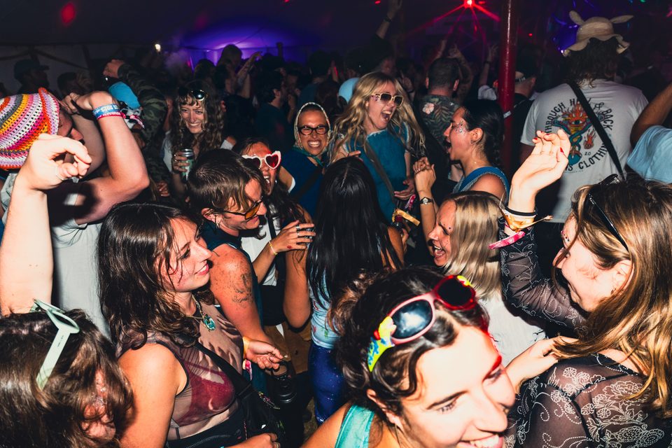 People dancing in a crowded indoor space with mixed lighting.