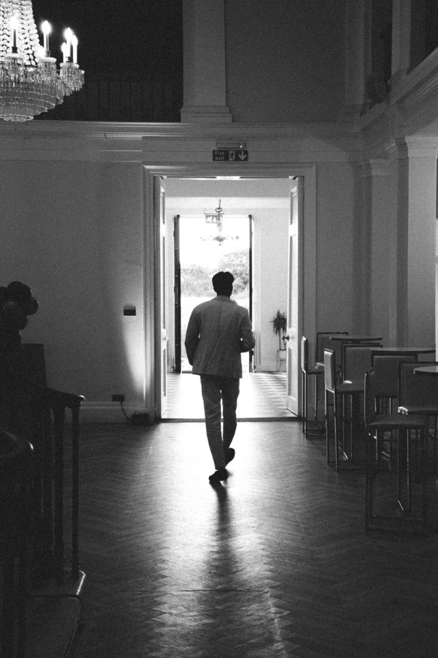 A person walks away from a brightly lit doorway in a dimly lit hall.