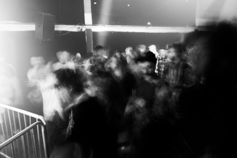 Blurred crowd in a dimly lit club with stage lighting.
