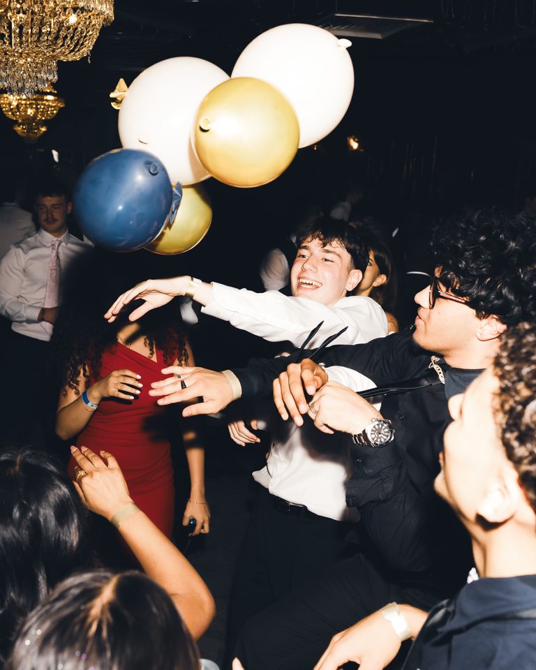 People dancing under balloons in a dimly lit indoor venue.