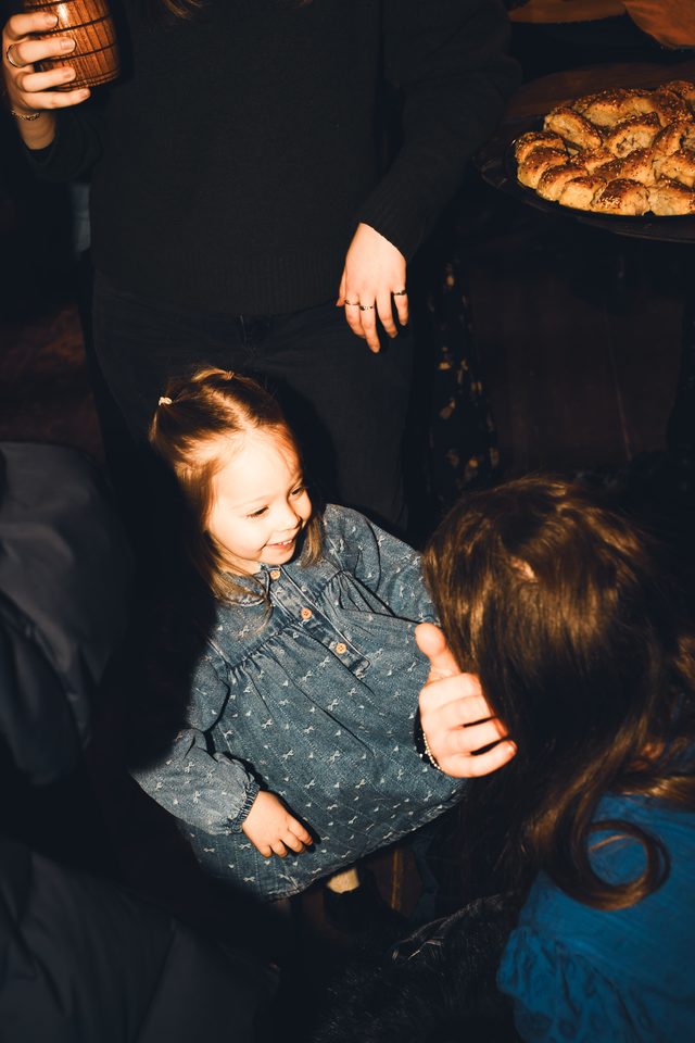 Two children interacting in a dimly lit indoor space with food visible in background.