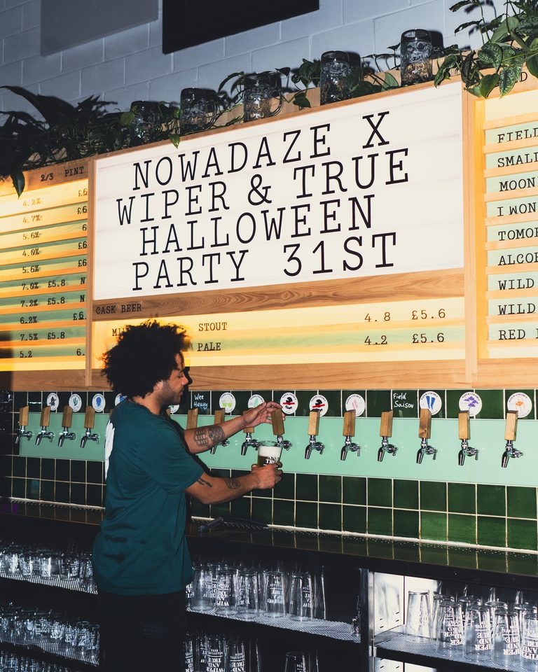 Bar worker pouring beer from tap under dim lighting.
